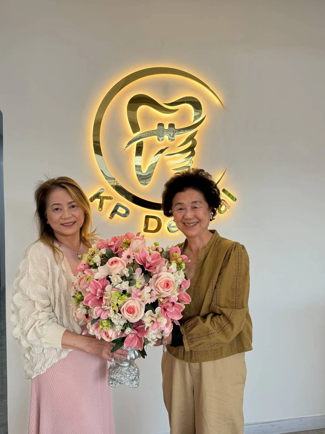A warm welcome with flowers beside the illuminated KP Dental Clinic logo